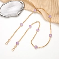 Detail of gold chain with purple smiley faces and lobster clasps on elegant tray - Purple
