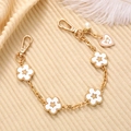 Detalle de cadena dorada con flores blancas de cinco pétalos y perla sobre punto - Cadena de mano / Blanco