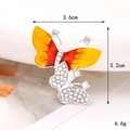 Détail macro de l'accessoire papillon strass montrant les dimensions 3,6cm par 3,2cm - Papillon orange