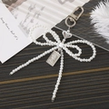 Portachiavi con fiocco di perle e ciondolo a cuore con rilievo su tavolo in legno - Stile Fiocco Perla Bianca (K3238)
