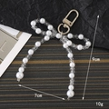 Detailed view of pearl bow pendant showing dimensions 9cm by 7cm with gold keychain - Clear
