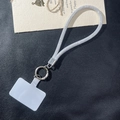 Close-up of sparkling silver rhinestone phone lanyard with a metal ring and plastic patch - White