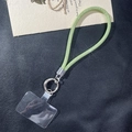 Detail of glittery lime green mesh phone strap with silver spring ring on black leather background - Green