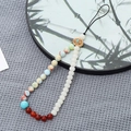 Detail of beaded phone strap featuring colorful stones and an antique decorative charm - Shoushan Stone + Bodhi Bead Style