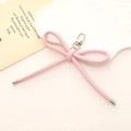 Dettaglio di un ciondolo a fiocco in pelle PU rosa con moschettone argentato e punte in metallo - Rosa Chiaro