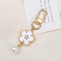 Detail of elegant gold flower keychain with white petals, star emblem, and pearl charm - Faux Shell Flower Style (K3606)