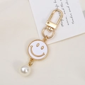 Detailed close-up of a gold alloy flower keychain with smile face and large pearl bead - Faux Shell Smiley Style (K3609)