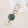 Close-up of a green smiley face keychain with a golden clasp and a pearl accent - Faux Shell Smiley Style (K3610)