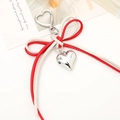 Detail of red and white leather bow charm with silver heart pendant and metal hook - White + Red