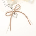 Detail of bicolor leather cord bow charm with silver heart pendant and spring clasp - White + Khaki