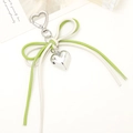 Close-up of heart-shaped silver pendant with green and cream leather bow keyring - White + Green