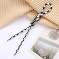 Detail of black and white houndstooth woven charm with a textured rope knot and plastic tips - Black+White