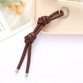 Minimalist brown leather knot keychain with silver ring on a decorative tray - Coffee