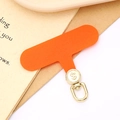 Macro detail of orange fabric phone tether tab with rotatable gold dollar sign metal hook - Orange (Gold Buckle)