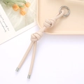 Porte-clés en cuir tressé beige avec un fermoir à anneau argenté sur un plateau - Attache PU Double Nœud (K4157) / Blanc Cassé