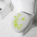 Close-up of green butterfly and floral vine stickers applied on white toilet lid - Fruit Green