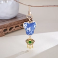 Dettaglio di un ciondolo cinese in seta ricamata con lucchetto dorato e gancio metallico - Blu