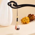 Close-up of ceramic lucky cat pendant with golden metal tags on wooden display - Black Lucky Cat (K5900)