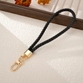 Detail of hand-woven black leather phone strap with premium gold metal clasp and ring - Charm / Black