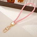 Rosa handgewebte PU-Leder-Handschlaufe mit goldener Schließe auf strukturiertem Hintergrund - Rosa
