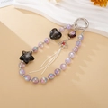 Detail of beaded star charm with silver fringe tassel and red diamond floral pendant - Black