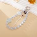 Close-up of heart and star beads with floral pendants on a silver metal keychain - Blue