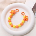 Detail der Handy-Perlenkette mit orangefarbenen Blumen und matten Perlen auf Keramiktablett - K949 Orangefarbene Blumenkette