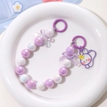 Macro detail of pearlescent bead phone strap with purple bow and cute bunny charm - Purple + White