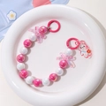 Macro detail of mermaid bead chain with acrylic rabbit pendant and pink bow charm decoration - Rose Red + White