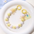 Close-up of yellow mermaid beads keychain with cute bear pendant and bow details - Yellow + White