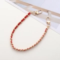 Close-up of golden metal chain interwoven with red leather and lobster clasps - Red