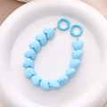 Close-up of sky blue faceted heart beads with spring ring clasps on ceramic plate - Blue