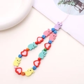 Macro shot of wooden flower beads and colorful letter blocks on a phone wrist strap - Sloth and Heart Style