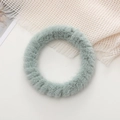 Close-up of soft sage green plush fur scrunchie bracelet on white and beige linen background - Green