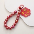 Nahaufnahme der roten Perlenkette mit Glücks-Acryl-Anhänger und praktischem Karabiner - Viel Glück / Irisierende Perle Große Vorzeichen Rot