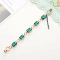 Close-up of rectangular emerald green crystal links with gold metal clasp and chain - Dark Green