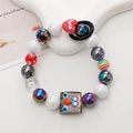 Close-up of colorful handmade beaded phone strap with a cute cartoon face charm - Gray Cartoon Baby