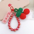 Macro detail of handmade crochet cherry charm with green leaves and red iridescent beads - Beaded Cherry Style