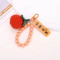 Close-up of hand-knitted orange persimmon keychain with colorful beads and metal hook - Beaded Red Persimmon Style