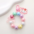 Pastel beaded bear keychain with iridescent pearls and a pink bow on white background - Rainbow