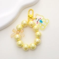 Close-up of iridescent yellow beaded charm with a cute bear pendant and a metal clip - Yellow