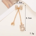 Dettaglio del ciondolo dorato da 8,5 cm con fiocco, strass, numero 5 e perla finta - Ciondolo Doppio Fiocco Strass n. 5 (D801)