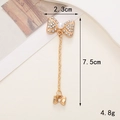 Dettaglio di un ciondolo a fiocco dorato con strass bianchi e perla centrale - Ciondolo a Fiocco Strass (D722)