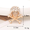 Dettaglio macro di un ciondolo per scarpe a teschio dorato con strass brillanti e misure - D119 Croce Teschio con Strass
