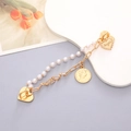 Detail of layered gold chain bracelet with white pearls, heart charms and vintage coin - K2401 Artificial Pearl Bracelet with Figure Head (Heart Clasp)
