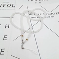 Detail of white beaded phone lanyard with golden crystal accents and silver metal clasp - White