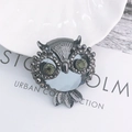 Vintage owl brooch featuring light blue faceted gemstone and dark yellow crystal eyes - Gunmetal Base Gray Owl