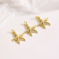 Détails de trois pendentifs étoile de mer dorés avec oxydes de zirconium sur marbre - Pendentif Étoile de Mer Doré (ZYN-DMK1239G)