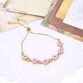 Close-up of golden adjustable bracelet with pink enamel stars and zircon evil eye details - Pink Star