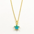 Close-up of blue star-shaped zircon pendant on gold-plated thin cross chain necklace - Teal Star Necklace